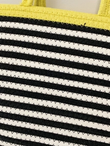 Close-up of woven tote bag showing black and white stripes with yellow trim texture