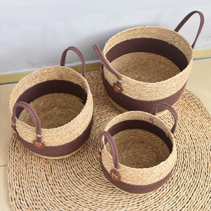 Three-piece seagrass woven basket set with dark brown handles and leather logo detail