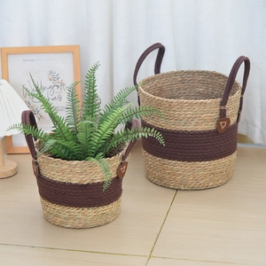 Detail of woven seagrass plant baskets with dark handles and reinforced leather patches