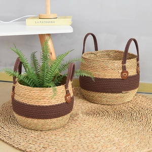 Detail of two-piece woven seagrass storage baskets with brown handles and leather accents