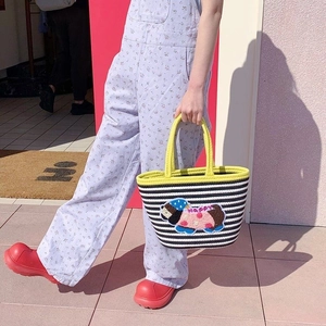 Detail of hand-woven tote bag with black stripes and vibrant yellow round handles