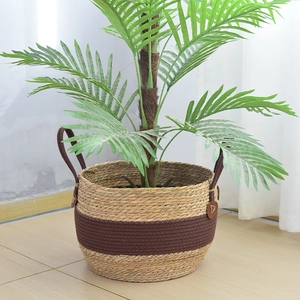 Detail view of woven seagrass plant basket with brown leather logo and side handles