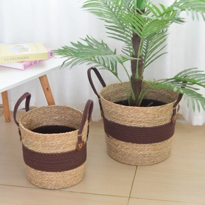 Detail of woven seagrass plant baskets with brown ribbon handles in a modern home setting