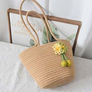 Dettaglio della borsa tote in paglia intrecciata con fiori gialli in maglia e spalline lunghe