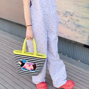 Close-up of woven tote bag with black stripes and happy cartoon dog embroidery