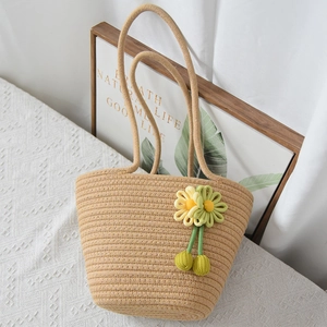 Dettaglio della borsa in paglia intrecciata con fiori in maglia fatti a mano e manici