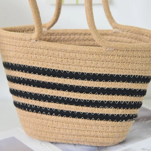 Gros plan d'un sac cabas en paille tissée avec rayures noires et détails en fibres