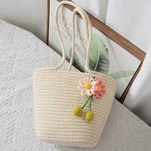 Dettaglio della borsa intrecciata con fiori all'uncinetto fatti a mano rosa e bianchi