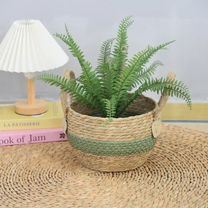 Detail view of a handmade seagrass woven planter basket with green stripe decoration