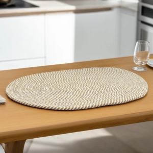 Makro-Detail des ovalen Baumwoll-Tischsets mit beiger und brauner Spiralstruktur auf Tisch