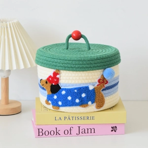 Close-up of woven gift basket featuring a dachshund embroidery and green lid for baby shower