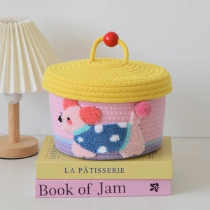 Detail of hand-woven cotton storage basket with yellow lid and dog embroidery