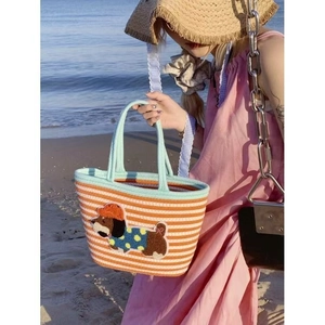 Close-up of woven striped tote bag with cute plush puppy patch and blue handles