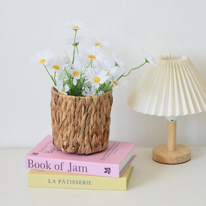 Detail of woven water hyacinth plant basket with white daisies on decorative books