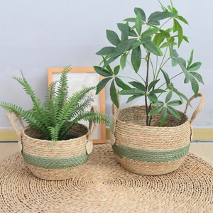 Detail of seagrass plant baskets set with green stripes and handles for home storage