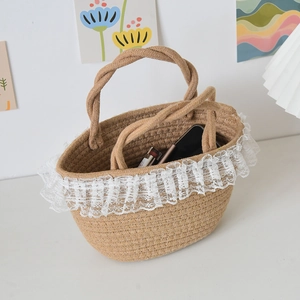 Detail shot of the woven straw bucket bag with white lace trim and twin rope handles