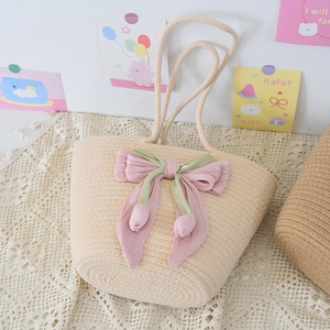 Detail of hand-woven straw bag with large velvet bow and tulip pendant decoration