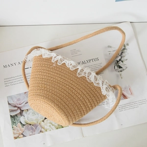 Top view of beige woven bucket bag with white lace trim detail on a magazine
