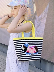 Detail of striped woven tote bag featuring a cute cartoon puppy patch and yellow handles