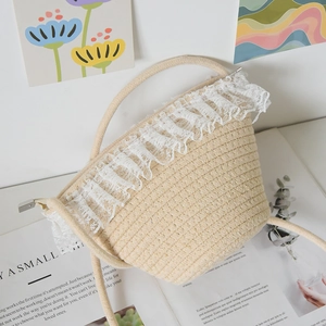 Detail of straw woven bucket bag featuring delicate white lace trim and rope handles