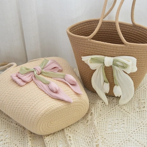 Detail of handmade woven straw bags featuring ribbon bows and 3D tulip floral charms