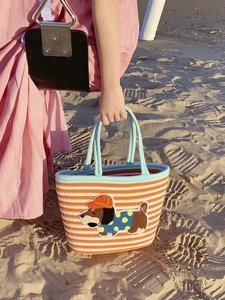 Close-up of a woven tote bag with orange stripes and a cute cartoon dog patch