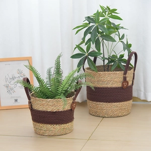 Set of two woven straw plant baskets with brown handles for indoor home decor