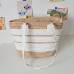 Detail of handwoven tote bag featuring cream stripes and sturdy faux leather handles