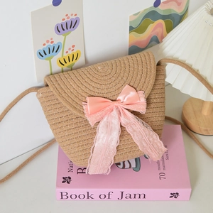 Detailed close-up of handmade woven straw bag with elegant pink lace bow and shoulder strap