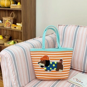 Orange and white striped knit tote bag with cute dog embroidery on a cozy sofa