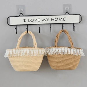 Detail of woven straw handbags with lace trim hanging on a decorative hook