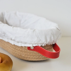 Oval bread proofing basket with white linen liner and red leather handles with rivets