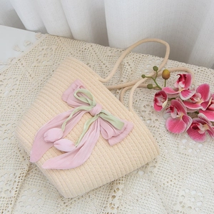 Handmade rainbow straw handbag with pink bow and floral charm on lace tablecloth