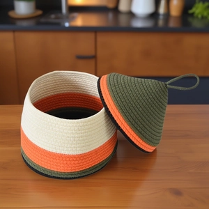 Close-up of three-color woven cotton rope storage basket with handle on wooden tabletop