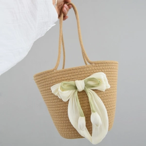 Detail of handmade straw bag featuring a cream chiffon bow and tulip floral charms
