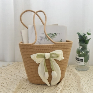 Close-up of brown woven handbag featuring a large green chiffon bow with floral buds
