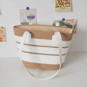 Close-up of a striped woven tote bag with white leather handles and beige zipper lining