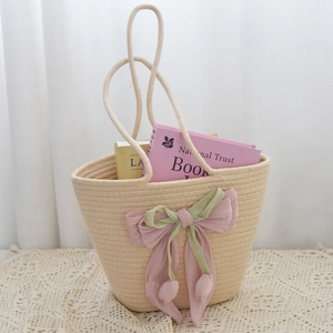 Detailed view of the woven cotton handbag featuring a large bow and tulip charms