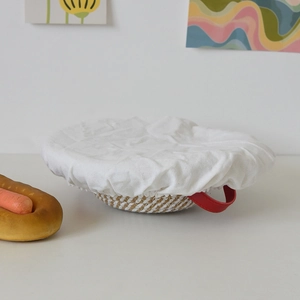 Close-up of woven rattan proofing basket with cotton liner and red handle for bread baking