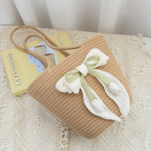 Detail of handmade woven bucket bag with elegant satin bow and tulip floral accents