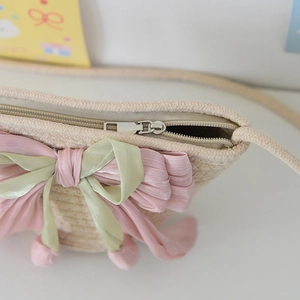 Close-up of woven bucket bag featuring metal zipper closure and cute fabric bow detail