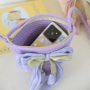 Detailed internal view of purple woven bucket bag with bow, showing smartphone storage capacity