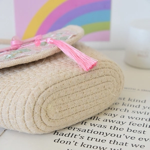 Detail of hand-woven cotton bag with floral embroidery and a pink fringe tassel