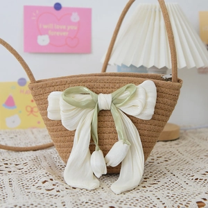 Detail of hand-woven straw bucket bag with large ribbon bow and tulip flower tassels