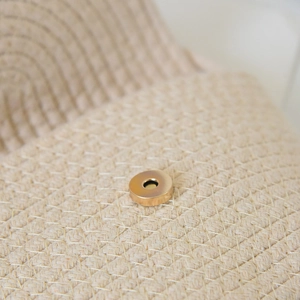 Detail shot of the bright gold magnetic metal buckle on a woven cotton tote bag