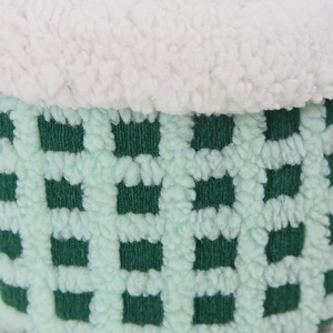 Close-up of green checkered plush fabric and soft white fleece trim on storage basket