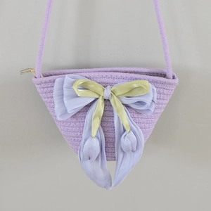 Close-up of lilac woven bucket bag featuring a large silk bow and tulip pendant detail