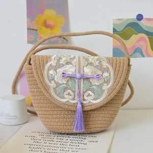 Detail of hand-woven cotton thread bag with floral embroidery and purple tassel