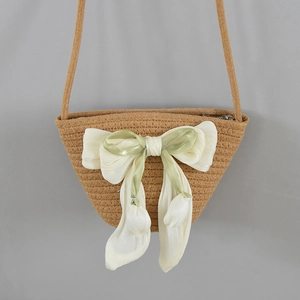 Close-up of woven straw bucket bag featuring a large cream and green decorative bow detail