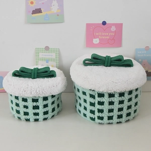 Detailed view of green checkered storage baskets with white fluffy lids and green bows
